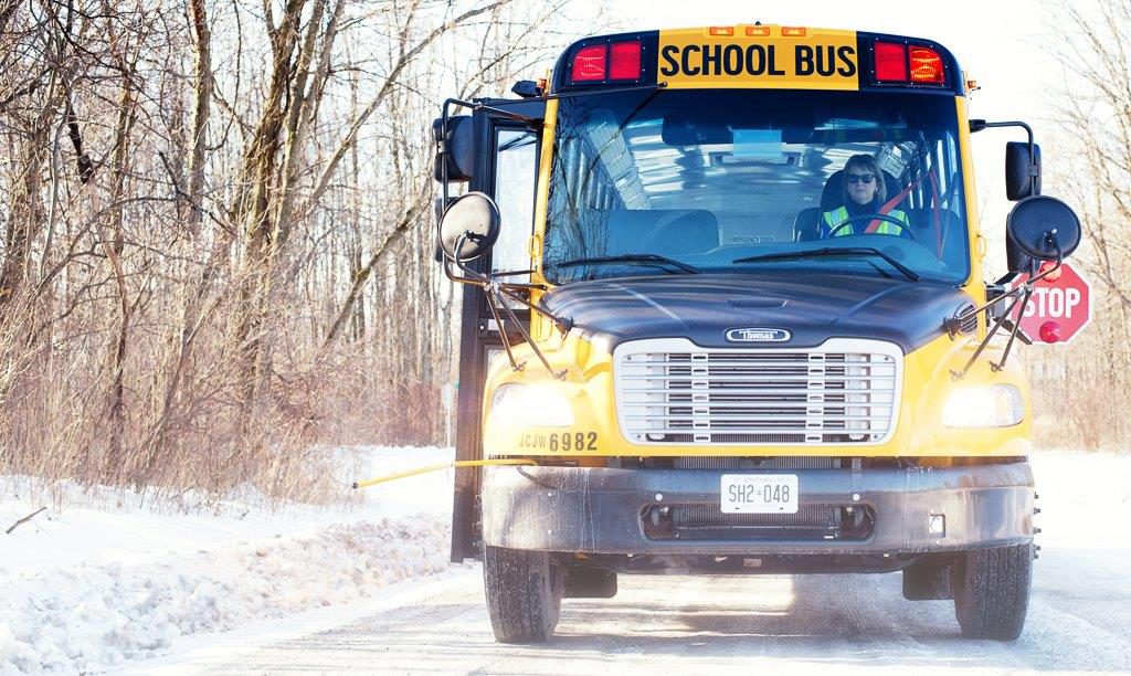 Yes school bus on snowy road with trees beside the ditch