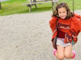 female student with a red sweater swinging on a swing set